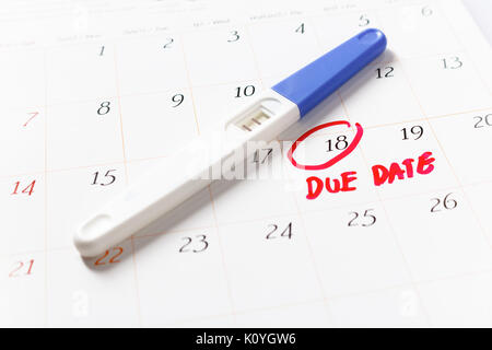 Pregnancy test with positive result lying on calendar; Due Date day; the 18th; Red circled on a white calendar; soft focus. Stock Photo