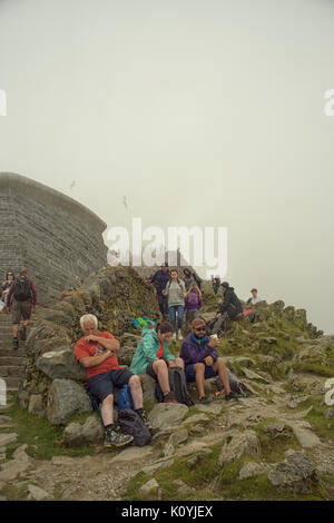 Crowds of walkers resting and taking in the view from the summit of Mount Snowdon Stock Photo