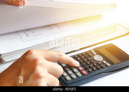 Financial data analyzing. savings, finances, economy. Close-up photo of a businessman's hand counting on calculator in office or home. Soft focus Stock Photo