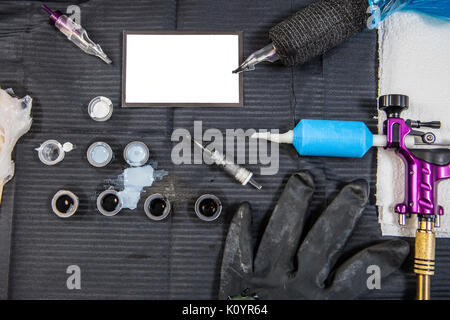 Tattoo artist table with objects and empty business card in the middle. Overhead shot Stock Photo