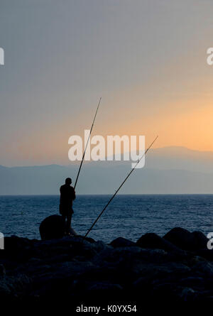 Fisherman silhouette on the beach at colorful sunset Stock Photo - Alamy