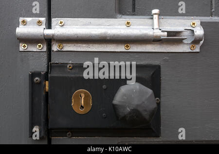 Close up of a lock, bolt, keyhole and door handle on secured wooden garden gate door Stock Photo