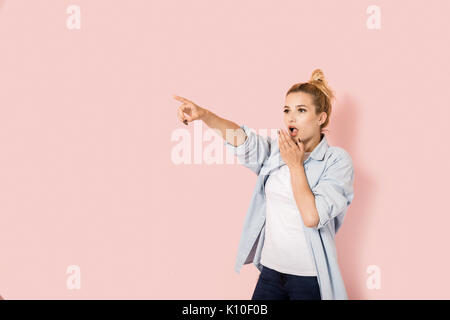 Surprised young woman pointing her finger at something Stock Photo