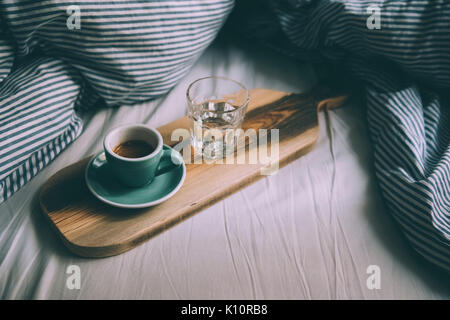 Beautiful morning working in bed essentials: Laptop and a fresh morning coffee with beautiful tiger crema on a wooden rustic hand-made tray Stock Photo