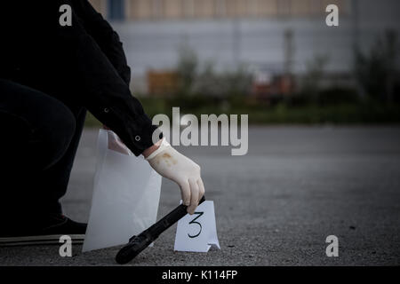 The crime scene, murder, investigation, police find rejected the gun used by the murderer, taken as evidence of the murder, an expert with rubber glov Stock Photo