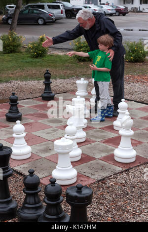 Grandfather teaching grandson how to play chess. Stock Photo