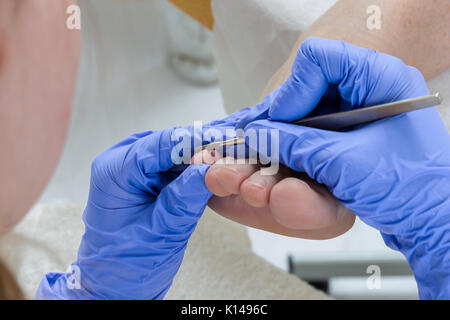 pedicurist Filing nails with metal instrument for rmoving nail surplus Stock Photo