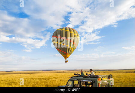 Early morning sightseeing and safari game viewing by colourful green hot-air balloon over the savannah plain and by jeep in Masai Mara, Kenya