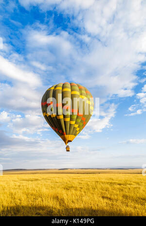 Early morning sightseeing and safari game viewing by colourful green hot-air balloon over the savannah plain in Masai Mara, Kenya