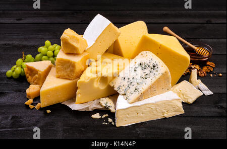 Various types of cheese on black wooden table. Stock Photo