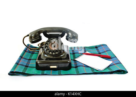 Vintage telephone on tartan plaid with red pen and notepad with copyspace isolated on white background Stock Photo
