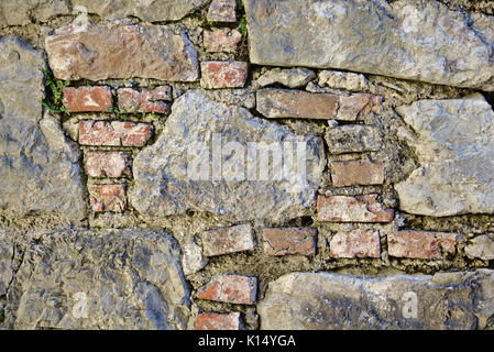 Ancient castle wall made of red bricks and large field stones with crumbling mortar Stock Photo