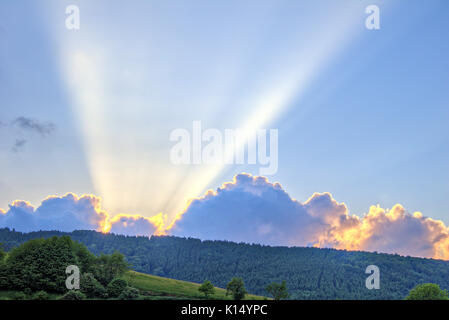 Sunset with rays of light over wooded mountain ridge Stock Photo