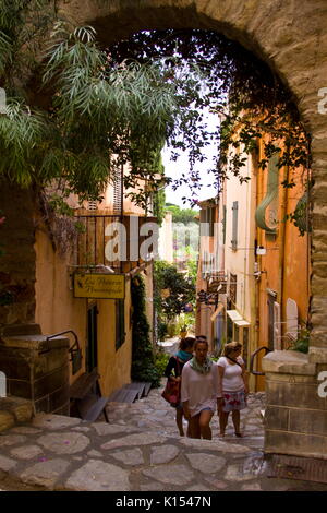 Tourists walking on cobbled streets Bormes les Mimosas Cote d Azur South of France Stock Photo