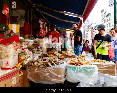 Pedestrian shoppers looking at items for sale in front of a Chinese food market shop, sidewalk in Chinatown, New York, NY, USA. Stock Photo