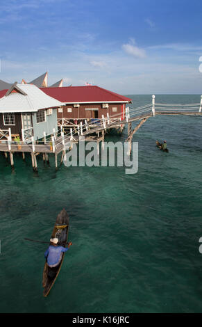 Sea gypsies in wooden canoes selling fresh seafood to guests at budget dive resorts on Mabul Island, Borneo Stock Photo