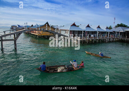 Sea gypsies in wooden canoes selling fresh seafood to guests at budget dive resorts on Mabul Island, Borneo Stock Photo