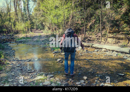 Travelers in the forest cross the stream Stock Photo