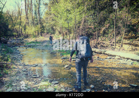 Travelers in the forest cross the stream Stock Photo