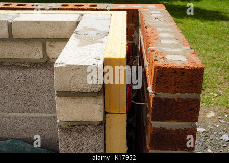 Insulation inside a new cavity wall with spacers between bricks and breeze blocks on a conservatory external dwarf wall. UK, Britain