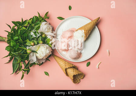 Pink strawberry and coconut ice cream, cones, white peony flowers Stock Photo