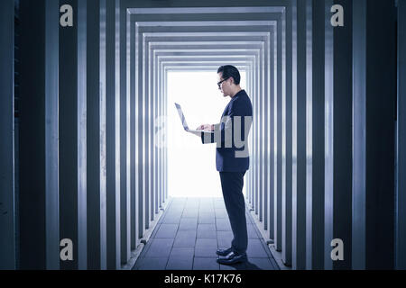Businessman using laptop with Line-shaped corridors background , night scene .