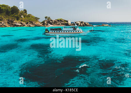 Tourist diving boat near island shore with turquoise clear transparent water. Idyllic view of Similan Islands Stock Photo