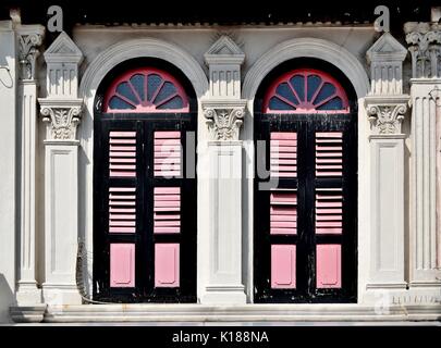 Traditional shop house exterior with pink wooden louvered shutters,  arched windows ornate columns in the Little India District of Singapore Stock Photo