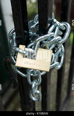 Heavy duty metal chain, rapped around gate, and padlocked. Chain and padlock. Stock Photo