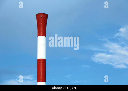 Red and white industrial chimney on blue sky background Stock Photo