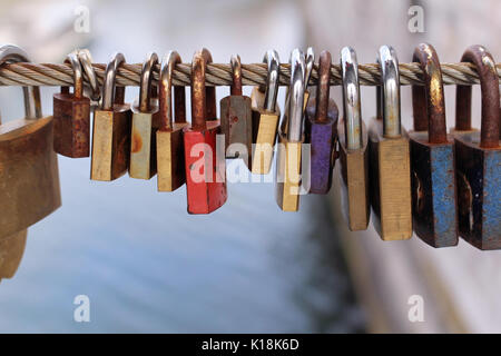 Old rusty padlocks left at the bridge fence as a symbol of eternal love Stock Photo
