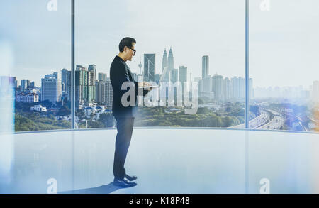 Businessman using laptop with generic office background , night scene . Stock Photo