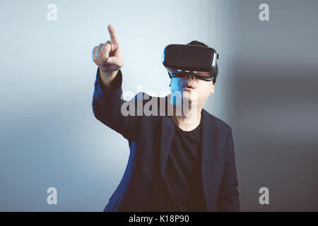Asian man wearing virtual reality goggle and pointing up . Stock Photo