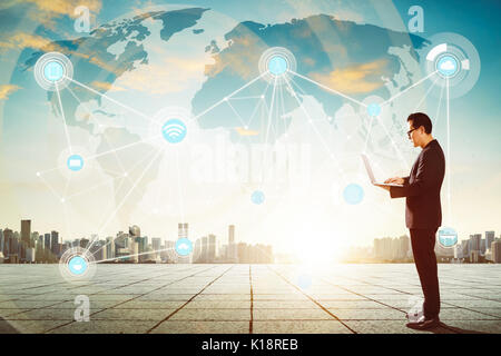 Businessman using laptop with smart city and wireless communication network background , evening scene . Stock Photo