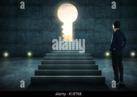 Hesitant businessman looking outside concrete wall with huge key shape door ,sunrise scene city skyline outdoor view . Stock Photo