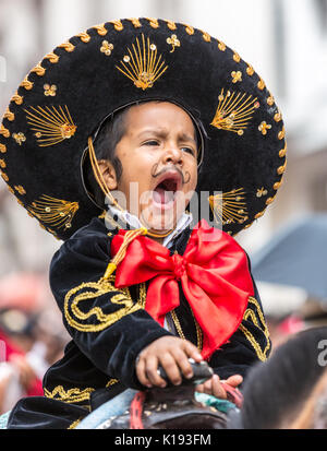 A young boy yawns on horseback in the Paseo del Nino parade in Cuenca, Ecuador on Dec 24,2014 Stock Photo