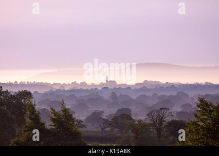 Flintshire, UK . With a warm day behind and clearing sky over Flintshire as the sun begins to break the horizon and the lighting the sky pink over the Cheshire Plain from the foothills of Flintshire