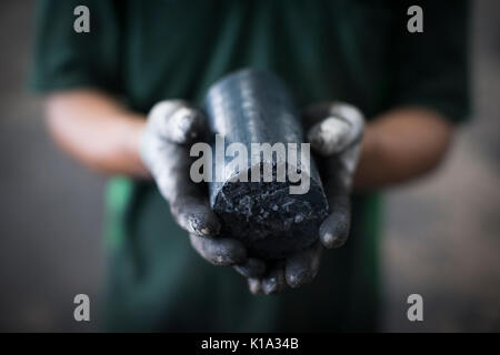 A worker holds a renewable energy source made from recycled soap and shampoo. It is made at a factory outside of Kuala Lumpur, Malaysia. Stock Photo