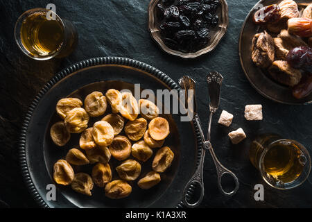 Dried apricots, dates and raisins on metal plates on a gray table horizontal Stock Photo