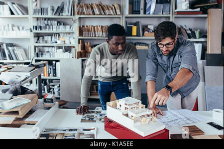 Two male architects working on a construction project in the office. Designers finalize a housing model house. Stock Photo