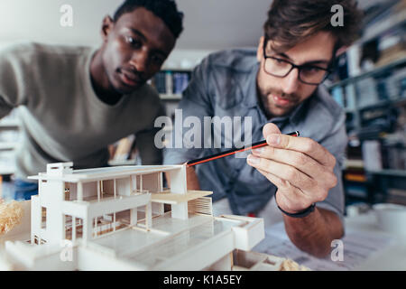 Two young architects working on new architectural house model. Designers looking at house model in studio. Stock Photo
