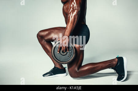 Low angle shot of healthy man exercising with weights. Cropped shot of african man with muscular build working out with barbell plate. Stock Photo