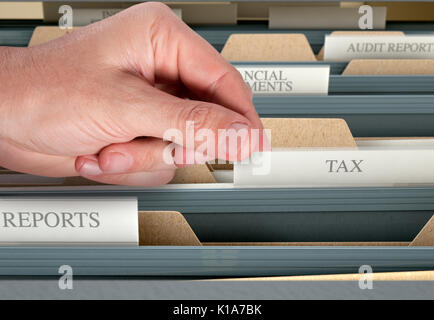 A male hand searching through documents in a filing cabinet drawer Stock Photo