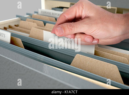 A male hand searching through documents in a filing cabinet drawer Stock Photo