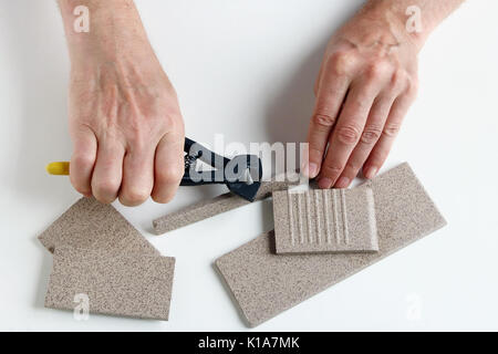 The old master ticks and cut the pieces of ceramic tiles on his work white table. Stock Photo