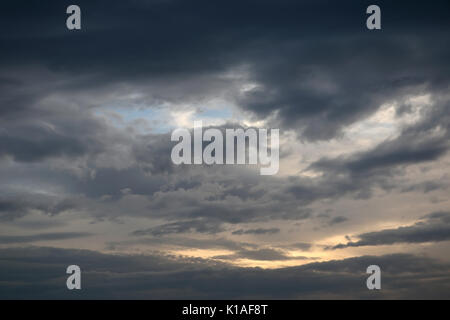 Dramatic stormy afternoon clouds, revealing a patch of blue sky behind them Stock Photo