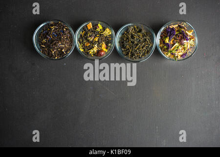 Different types of tea, green tea, peony and ginger tea, rose bud and wild flowers tea on dark wooden background with copyspace Stock Photo