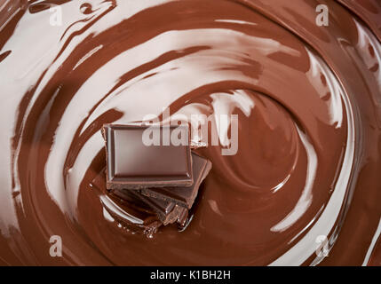 Melted pieces of chocolate bar in chocolate splash swirl Stock Photo