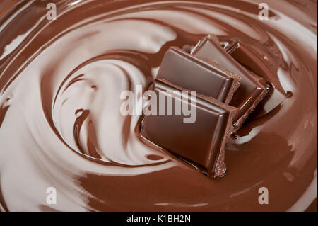 Melted pieces of chocolate bar in chocolate splash swirl Stock Photo