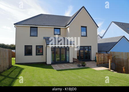 A modern design of house with its neatly maintained lawn and fresh looking rear face showing garden access for those summer days. Stock Photo